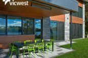 exterior patio of modern home with table surrounded by eight green chairs