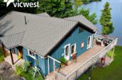 aerial view of cottage on lake with balcony and new roof