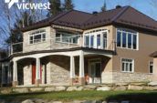 exterior of home with new roof and large balcony with white railings on second floor