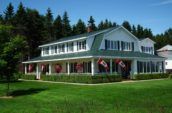 exterior of home with new green metal roof and four canadian flags hanging from porch