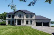 exterior of large grey home with new roof and big front lawn