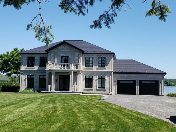 exterior of large grey home with new roof and big front lawn